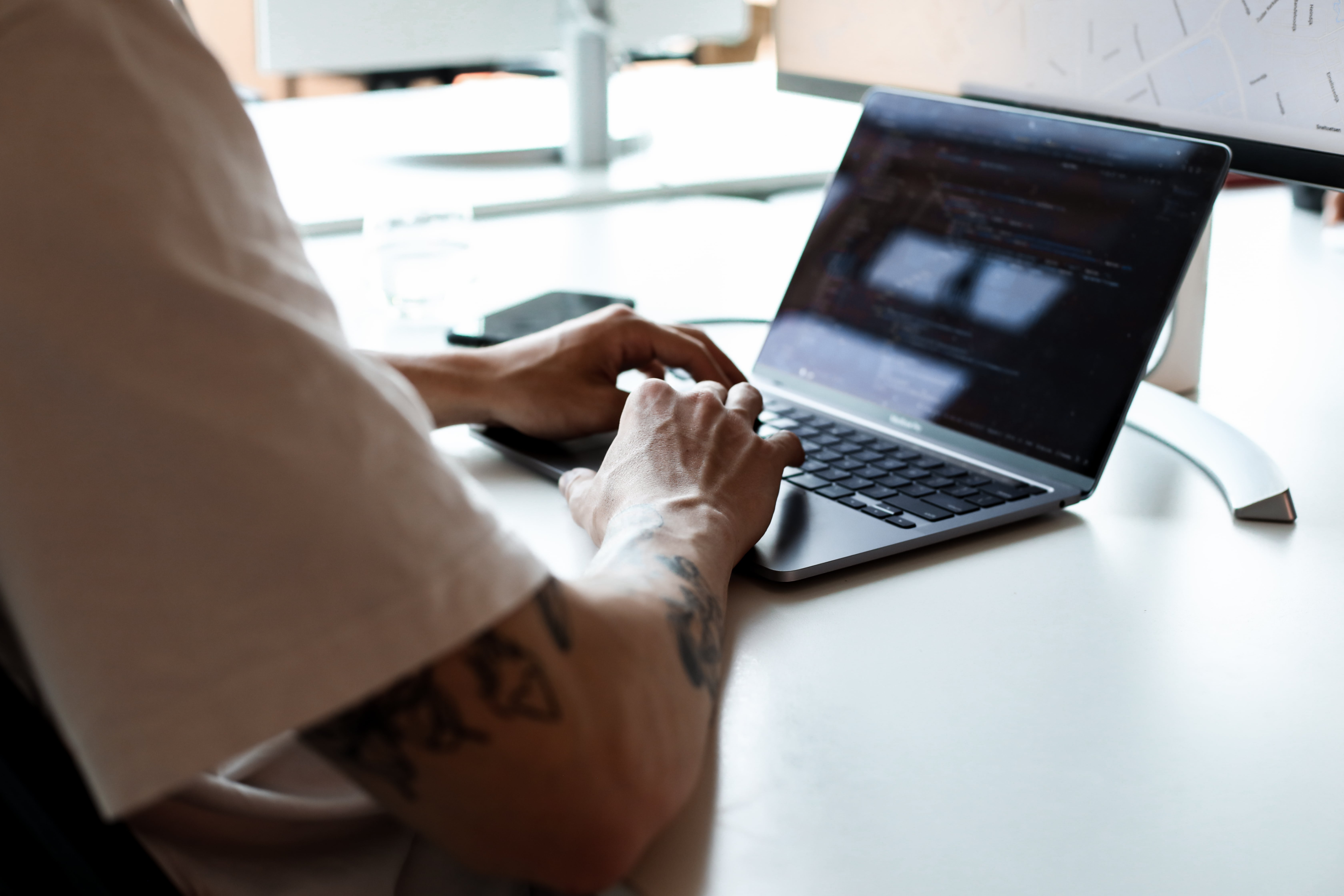 Persoon aan het programmeren achter zijn laptop